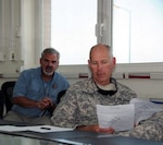 Army Maj. Loren Adams, right, the veterinary officer for the Iowa National Guard's 734th Agribusiness Development Team, reviews a document while Dr. Jim McCord, the U.S. Department of Agriculture veterinarian assigned to Regional Command-East, looks on during a meeting on veterinary policy in Kabul, Afghanistan, Oct. 12, 2010.