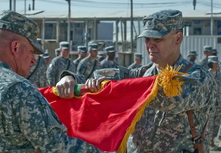 Brig. Gen. Philip R. Fisher, incoming commander of Joint Support Command-Afghanistan, unfurls the colors for the Mississippi National Guard's 184th Expeditionary Sustainment Command during the Joint Sustainment Command-Afghanistan transfer of authority ceremony at Kandahar Airfield, Afghanistan, Oct. 17, 2010.