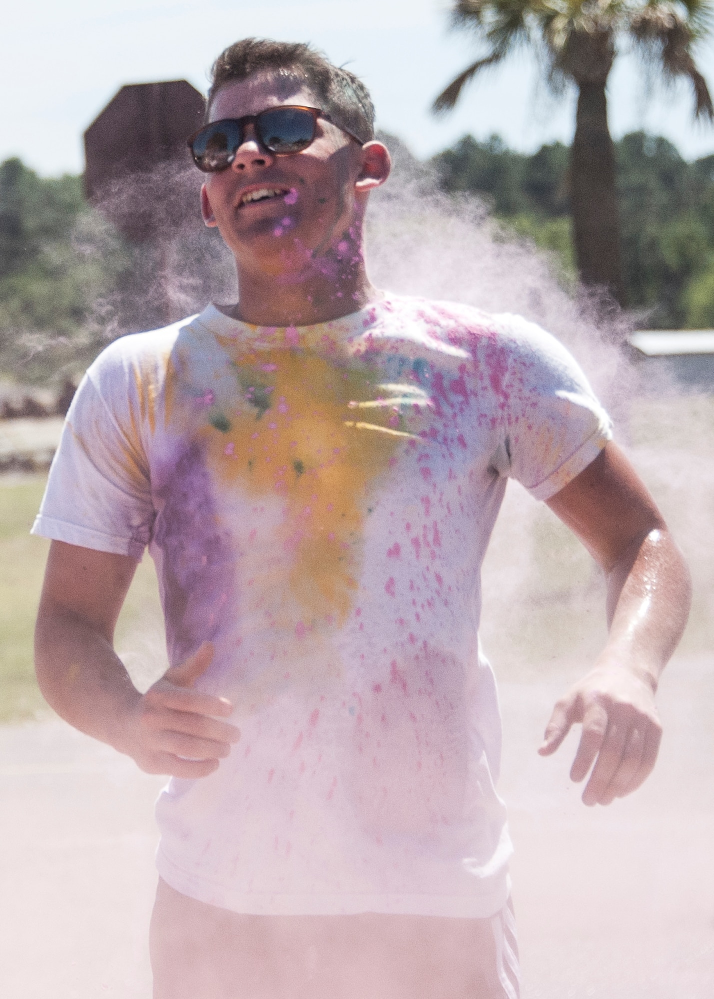 A participant runs through a cloud of pink dust at a color station during the Color Me Aware Fun Run, April 30, at Eglin Air Force Base, Fla.  Approximately 20 volunteers tossed powdered colors on more than 400 runners and walkers during the three-mile run.  The event closed out Sexual Assault Awareness Month activities. (U.S. Air Force photo/Ilka Cole)