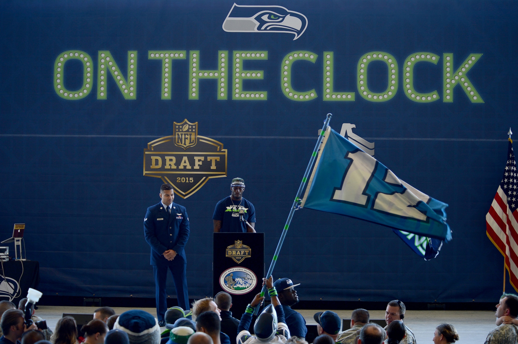 Airman 1st Class Michael Andrews (left), 10th Airlift Squadron loadmaster, stands next to Douglas McNeil, Seattle Seahawks wide receiver, before he announces this year’s draft pick May 2, 2015, during the Seattle Seahawks draft day event at Joint Base Lewis-McChord, Wash. During the event, the Seahawks selected a service member from each military branch to announce their picks for this year. (U.S. Air Force photo/Airman 1st Class Keoni Chavarria)