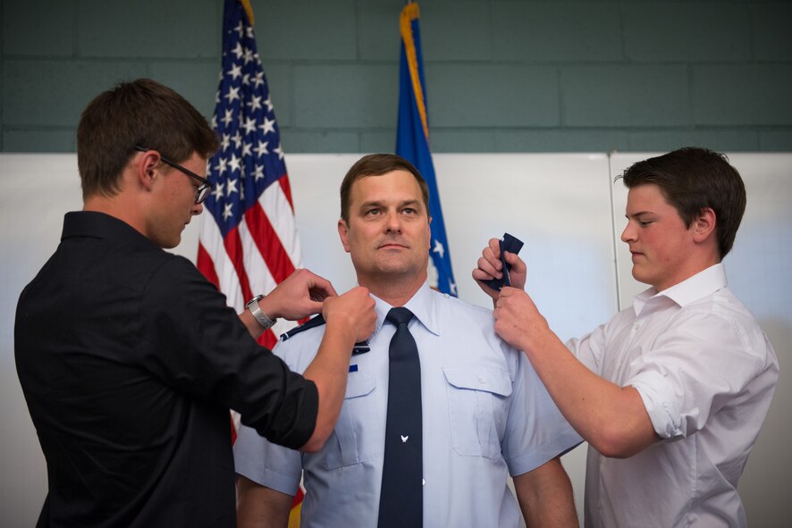 Col. Scott Calvert, 934th Mission Support Group deputy commander, stands as his sons pin on his newly achieved rank.  The colonel was recognized for his work within the Force Support Squadron during a promotion ceremony with his family, friends, and coworkers at the Minneapolis-St. Paul Air Reserve Station, Minn.  (U.S. Air Force photo by Staff Sgt. Corban Lundborg/Released)