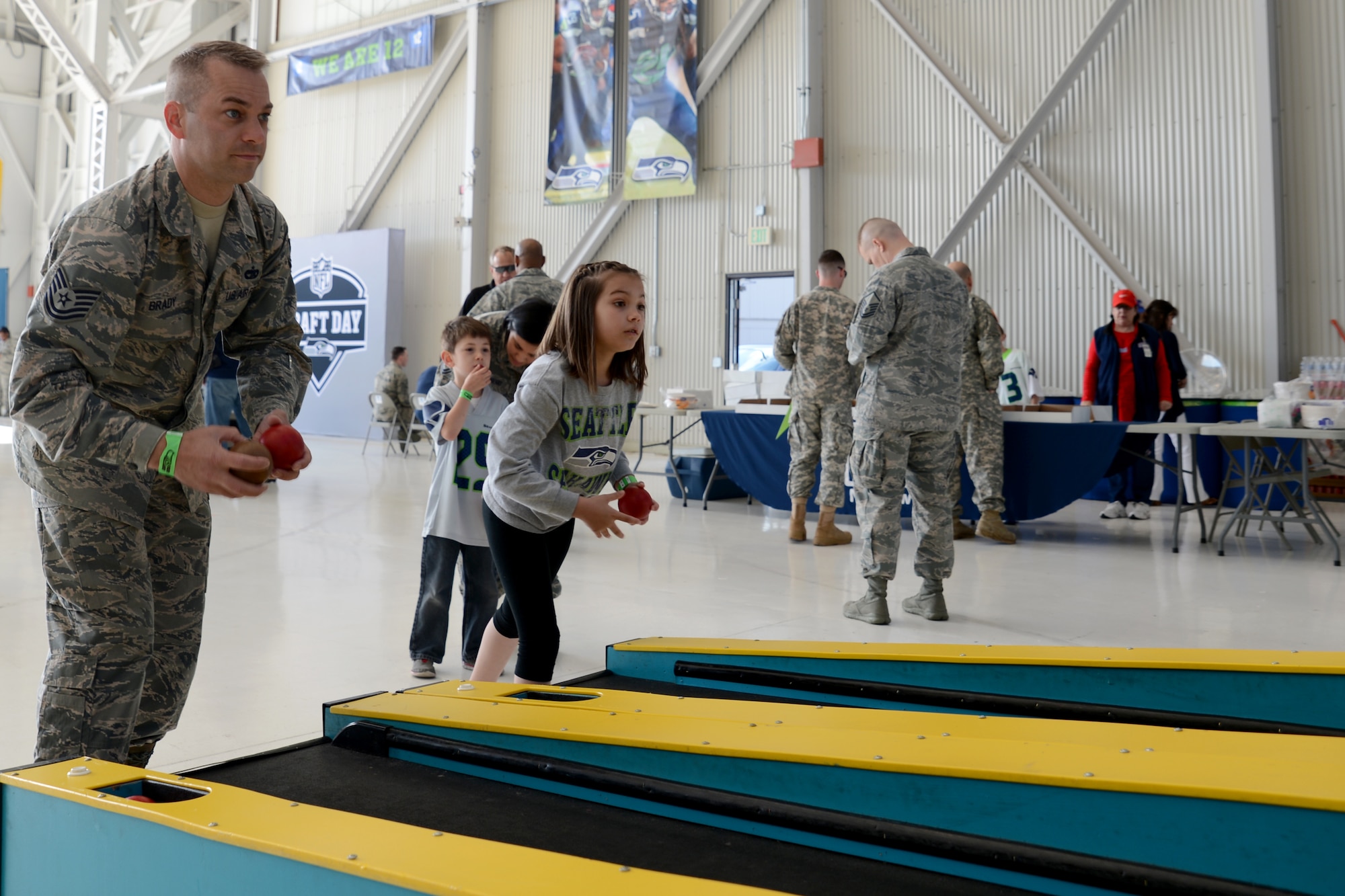 Tech. Sgt. Tim Brady, 62nd Aerial Port Squadron Air Terminal Operations Center senior controller, plays skee ball with his daughter during the Seattle Seahawks draft day event on Joint Base Lewis-McChord, Wash., May 2, 2015. More than 1,500 fans attended the event which included a mock NFL Combine, numerous gaming events to include armchair quarterback, shuffle board, pool tables, a football toss and kick game, photos with the 2013 Lombardi and 2014 National Football Conference championship trophies, video gaming, autographs from eight different Seahawk players, free food and drink and numerous military statics from across the Sound. (U.S. Air Force photo\ Staff Sgt. Tim Chacon) 