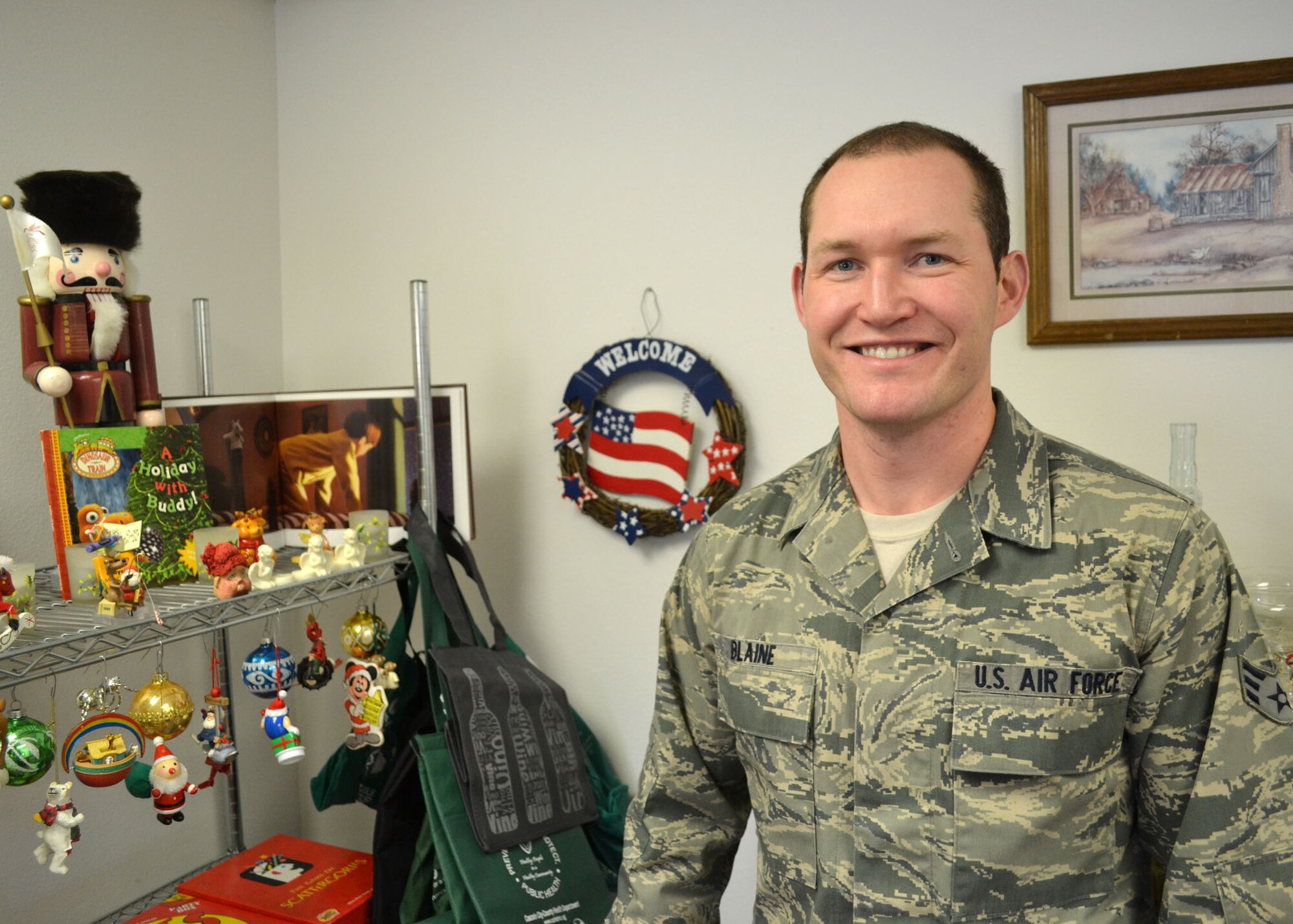 Comptroller Journeyman Senior Airman Nate Blaine shows off some of the items offered for free to members of the Montana Air National Guard at the new Airman’s Attic ran by members of the Junior Enlisted Council and the Family Readiness Program. The Airman’s Attic opened for business on Dec. 6, 2014 at the 120th Airlift Wing. Air National Guard photo by Senior Master Sgt. Eric Peterson.
