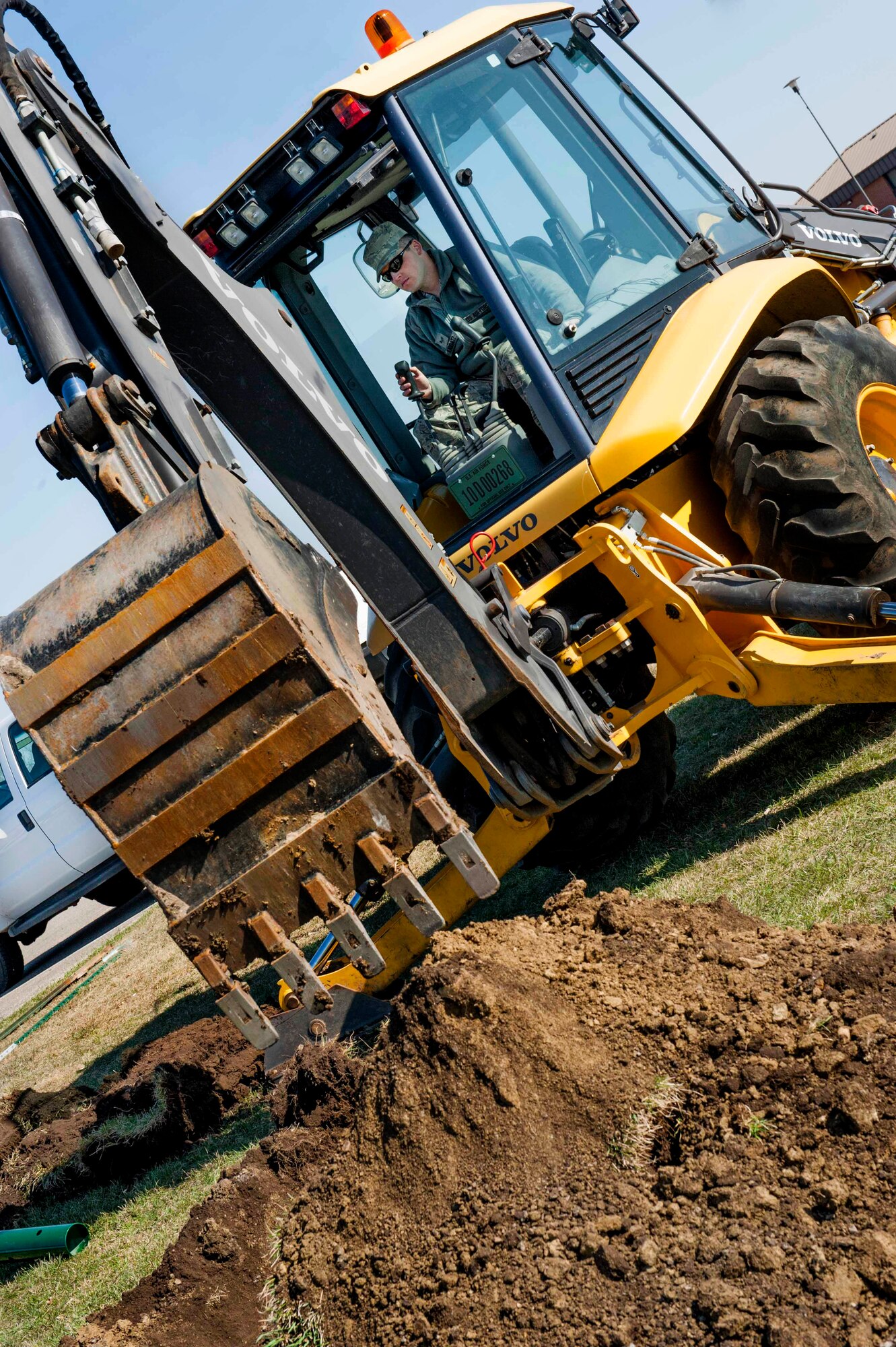 Senior Airman Nicholas Kaddatz, 5th Civil Engineer Squadron pavement and equipment, removes a section of dirt with a back hoe on Minot Air Force Base, N.D., April 23, 2015. The hole was dug in preparation for new gym equipment that is slated to be installed near the outdoor track. (U.S. Air Force photo/Airman 1st Class Sahara L. Fales)