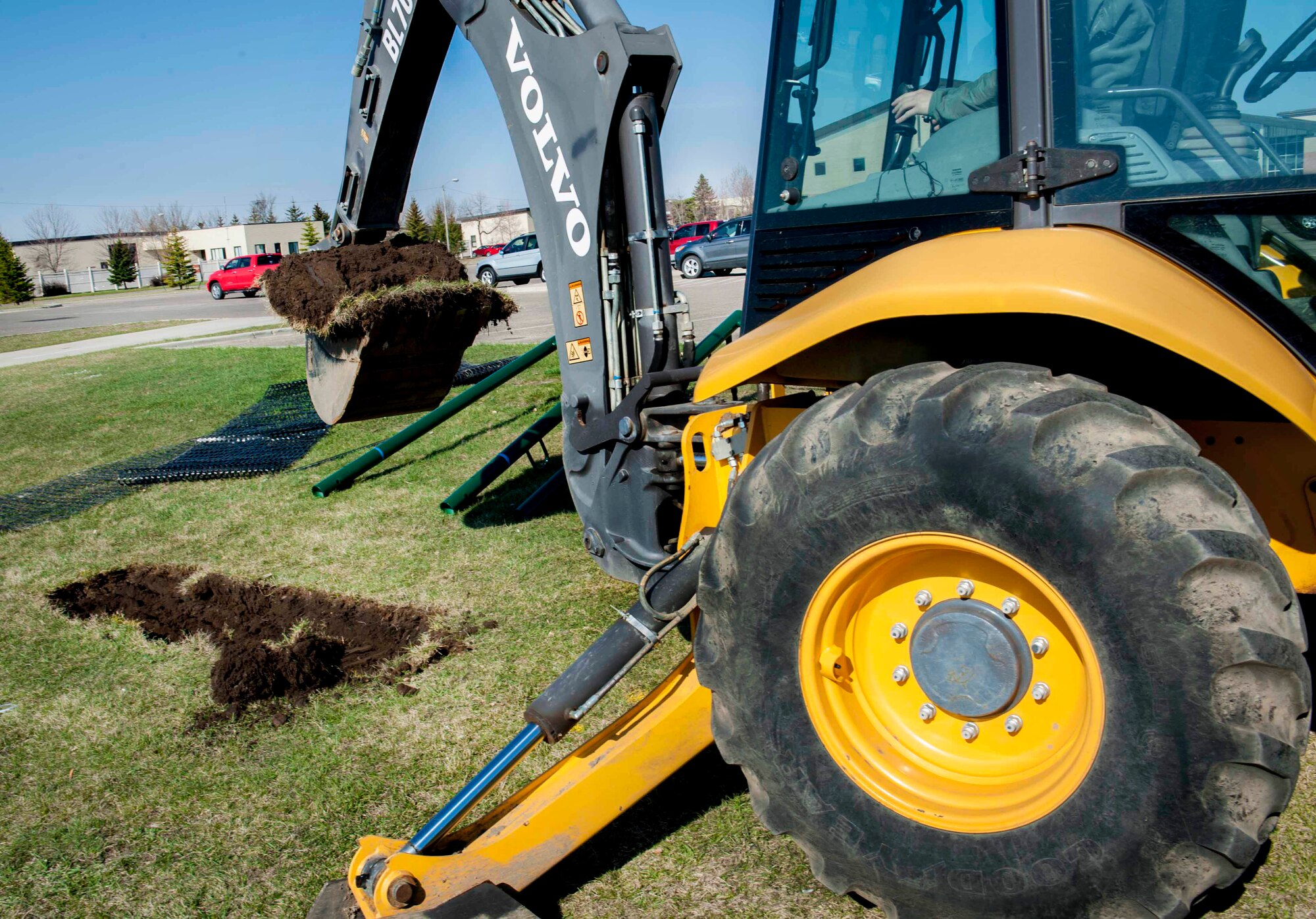 A member of the 5th Civil Engineer Squadron removes a section of dirt with a back hoe on Minot Air Force Base, N.D., April 23, 2015. The hole was made for placement of new pull up bars that are going to be installed by the outdoor track at the McAdoo Fitness Center. (U.S. Air Force photo/Airman 1st Class Sahara L. Fales)