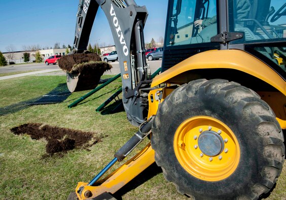 A member of the 5th Civil Engineer Squadron removes a section of dirt with a back hoe on Minot Air Force Base, N.D., April 23, 2015. The hole was made for placement of new pull up bars that are going to be installed by the outdoor track at the McAdoo Fitness Center. (U.S. Air Force photo/Airman 1st Class Sahara L. Fales)