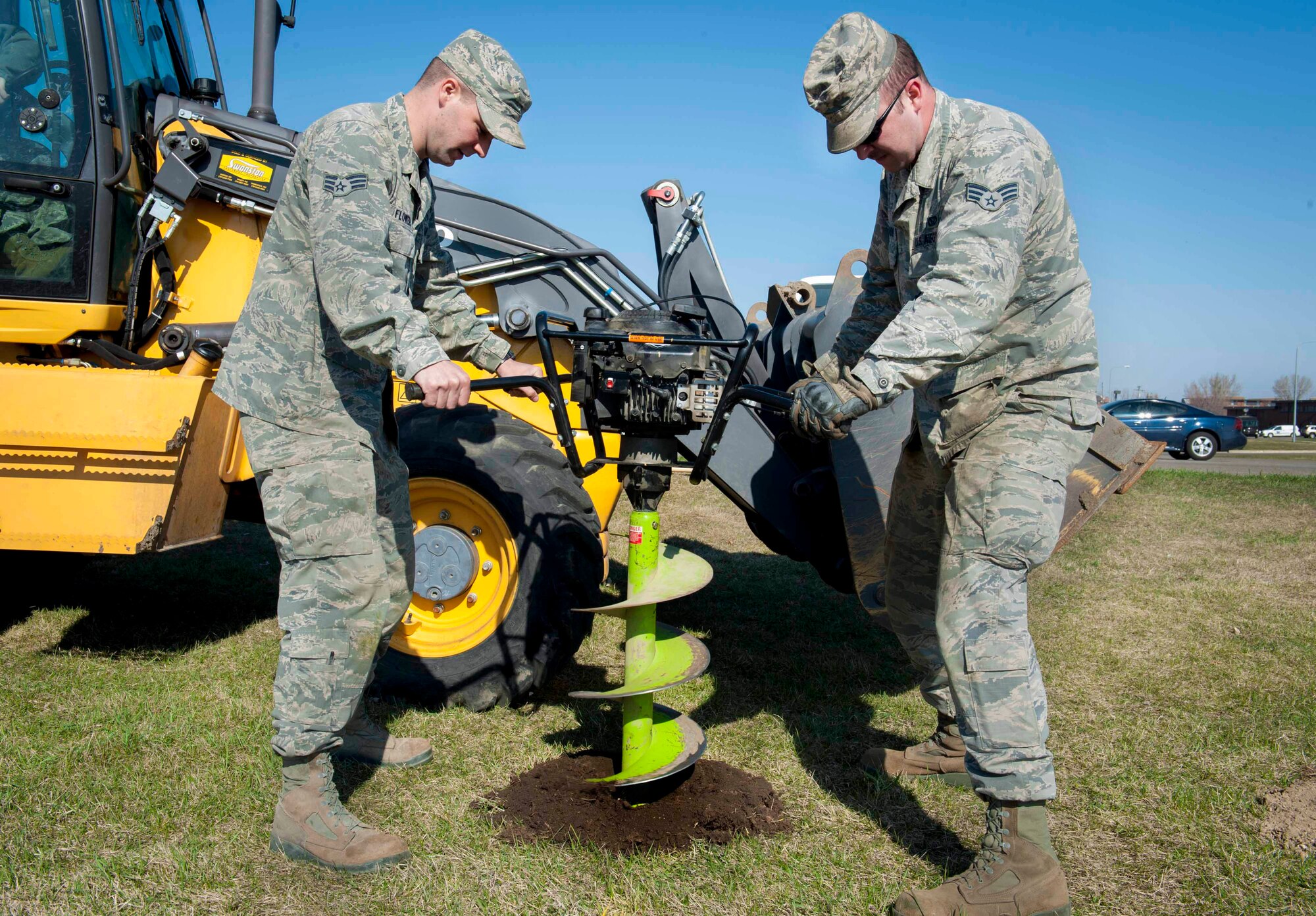 Senior Airmen Zachary Flowers and Anthony Lombardo, 5th Civil Engineer Squadron pavement and equipment, remove sections of dirt with an auger on Minot Air Force Base, N.D., April 23, 2015. The holes were drilled in preparation for new gym equipment that is going to be placed near the outdoor track. (U.S. Air Force photo/Airman 1st Class Sahara L. Fales)