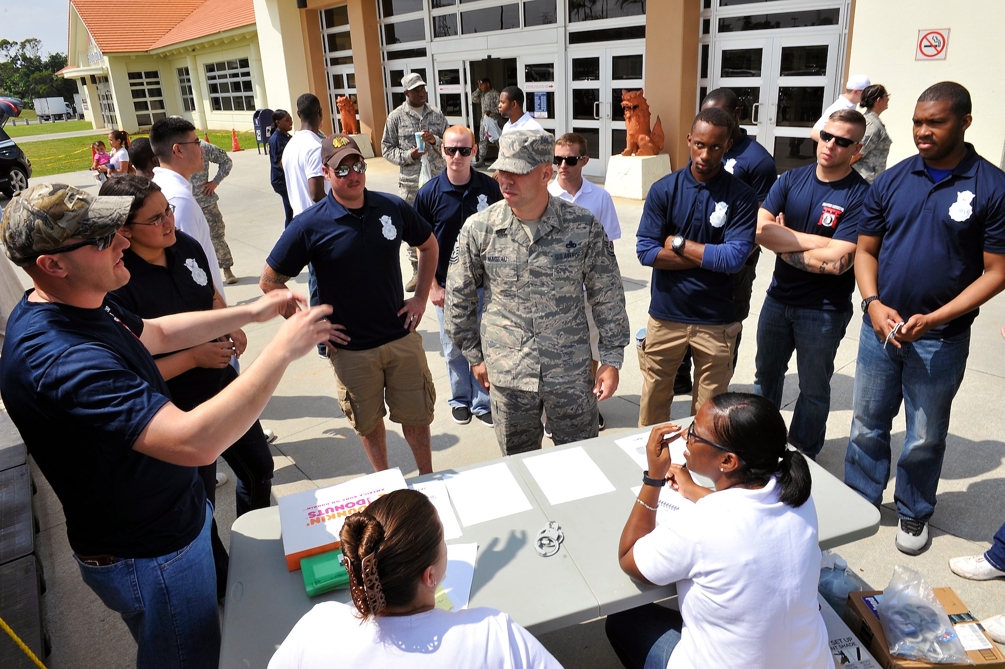 U.S. Air Force Staff Sgt. Robert Evilsizer (left), 18th Security Forces Squadron military working dog handler, explains the Jail and Bail system to Master Sgt. Joseph Mageau (center), 18th Civil Engineer Group first sergeant, at the Exchange on Kadena Air Base, Japan, May 1, 2015. In addition to the "Jail and Bail," Police Week included the defenders challenge, an open house, a "boots and utes" run, a 24-hour vigil run and a memorial service for the Airmen throughout May 10-16. (U.S. Air Force photo by Naoto Anazawa)