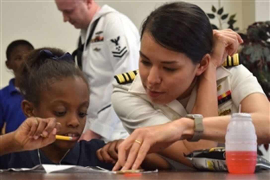 U.S. Navy Lt. Cmdr. Maura Thompson helps a child complete homework during Shreveport Navy Week in Shreveport, La., April 29, 2015. The child participates an after-school program through Volunteers of America.