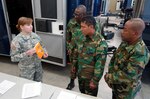 U.S. Army Sgt. Kelley Trebesch, 82nd Civil SupportTeam, South Dakota National Guard, discusses hazardous material storage with three members of the Suriname Defense Force at Ellsworth Air Force Base, S.D.,April 14, 2015. The SDNG and Suriname soldiers participated in a subject matterexpert exchange where they visited several units and facilities and discussedprotocols and processes for storing, using and disposing of hazmat. 