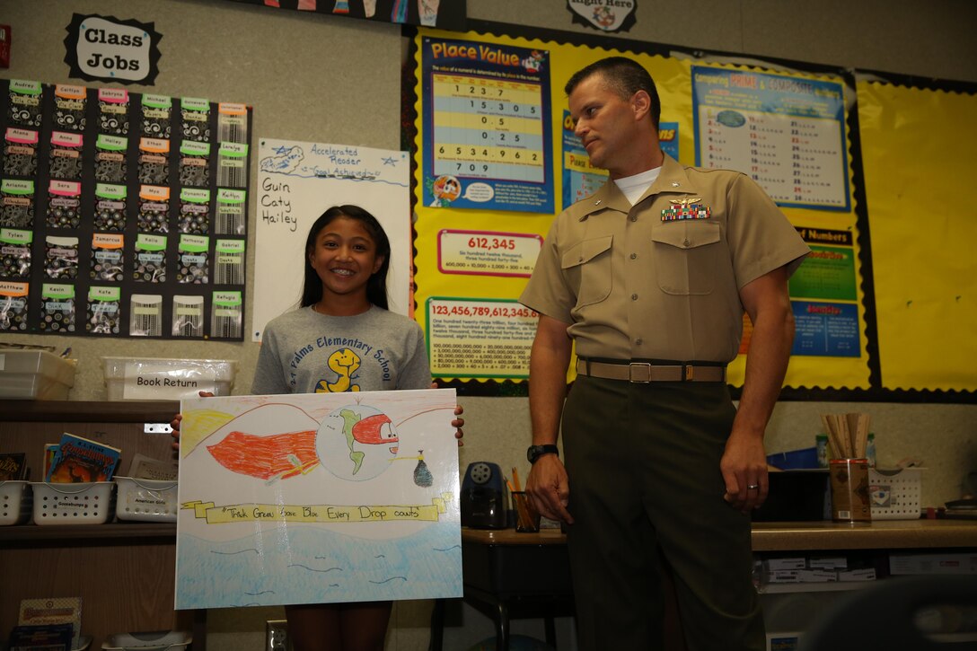 Kate Bobadilla, Earth Day poster finalist, Twentynine Palms Elementary, presents her poster to the class while being recognized by Lt. Col. Timothy Pochop, director, Natural Resources and Environmental Affairs, for being a finalist in the Earth Day Poster Contest, May 1, 2015. Bobadilla was the grand finalist, getting the most votes out of all nine contestants. (Official Marine Corps photo by Lance Cpl. Thomas Mudd/Released)