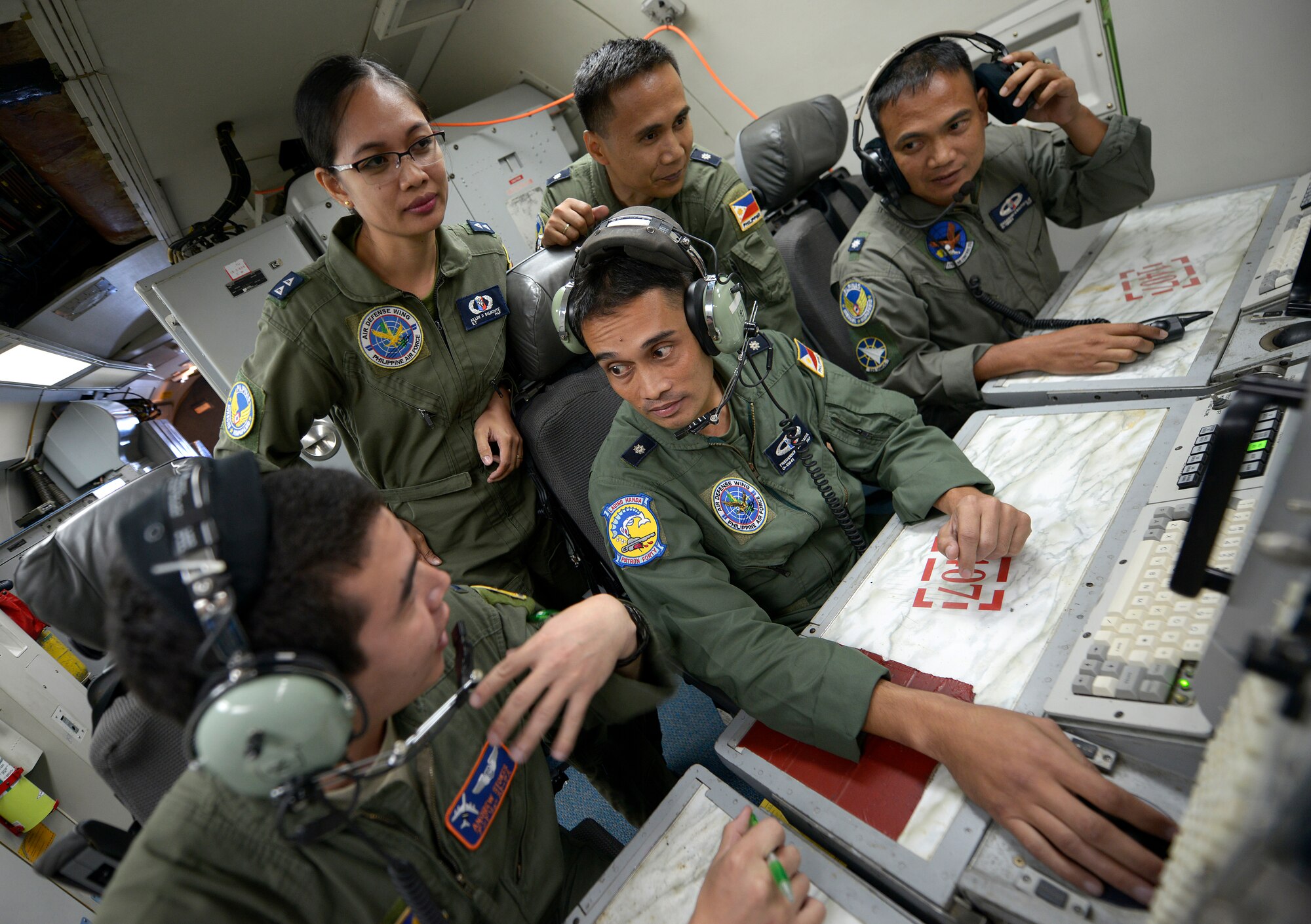 U.S. Air Force 1st Lt. Andrew Stokes, 961st Airborne Air Control Squadron (AACS) air weapons officer, speaks with Philippine Air Force Maj. Frederick Facia, 581st Aircraft Control and Training Squadron commander, and other PAF air battle managers while onboard a 961st AACS E-3 Sentry Airborne Warning and Control System (AWACS) during exercise Balikatan 2015 over the Philippines April 23. This exercise marks the first time in history that PAF air battle managers have controlled other aircraft while onboard the AWACS. Since the exercise began, April 20, the 961st AACS has integrated 20 PAF weapons controllers during their missions in order to provide them with first-hand experience using the aircraft’s systems. The 961st AACS is stationed at Kadena Air Base, Japan. (U.S. Air Force photo by Staff Sgt. Maeson L. Elleman)