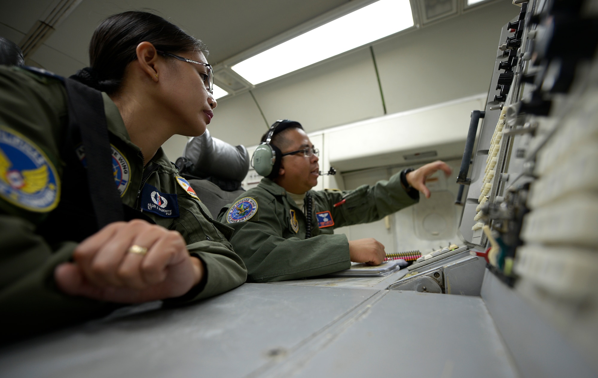 U.S. Air Force Master Sgt. Roberto Abcede, 961st Airborne Air Control Squadron senior surveillance technician (right), discusses procedures with Philippine Air Force 1st Lt. Aillen Balmonte, 581st Aircraft Control and Training Squadron air battle manager, while onboard a 961st AACS E-3 Sentry Airborne Warning and Control System during Exercise Balikatan 2015 over the Philippines April 23, 2015. This exercise marks the first time in history that PAF air battle managers have controlled other aircraft while onboard the AWACS. Since the exercise began April 20, the 961st AACS has integrated 20 PAF weapons controllers during their missions to provide them with first-hand experience using the aircraft’s systems. The 961st AACS is stationed at Kadena Air Base, Japan. (U.S. Air Force photo by Staff Sgt. Maeson L. Elleman) 