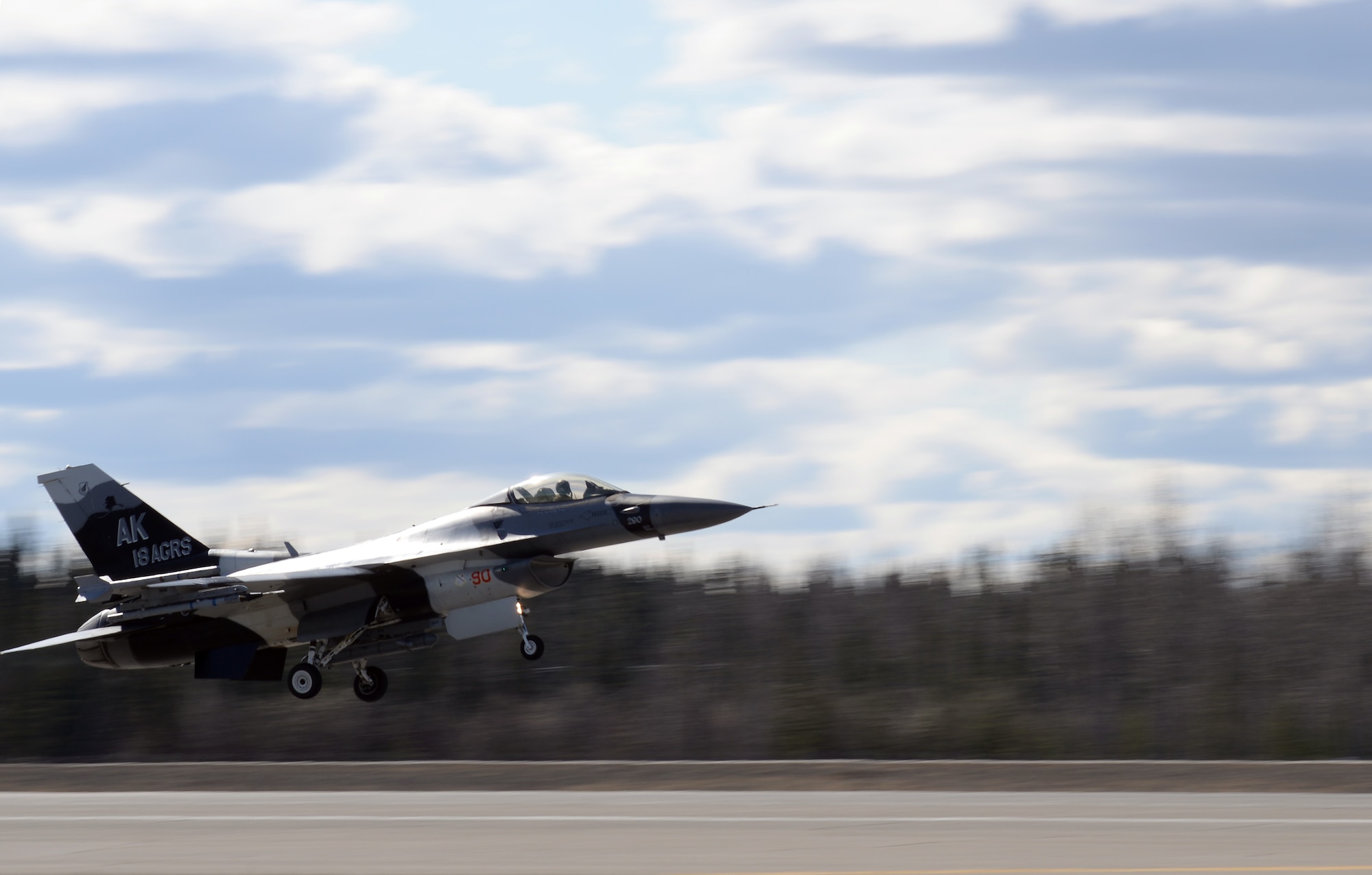 A U.S. Air Force F-16 Fighting Falcon aircraft assigned to the 18th Aggressor Squadron takes off from Eielson Air Force Base, Alaska, April 27, 2015, to participate in a Distant Frontier mission with F-16 pilots and aircraft deployed from the 113th Wing, District of Columbia Air National Guard. Distant Frontier provided the deployed pilots an opportunity to fly orientation flights in the more than 67,000 square-mile Joint Pacific Alaska Range Complex, become familiar with local flying restrictions, receive local safety and survival briefings, and develop orientation plans during the week prior to RED FLAG-Alaska 15-2, a Pacific Air Forces-directed field training exercise flown under simulated air combat conditions to increases combat capability. (U.S. Air Force photo by Master Sgt. Karen J. Tomasik/Released)