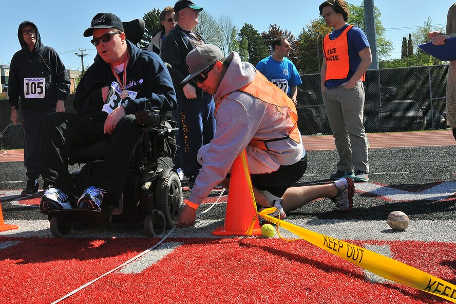 Senior Airman Juan Guerrero, 92nd Logistics Readiness Squadron vehicle maintenance and analysis specialist, measures the distance of a tennis ball throw while Erik Migliaccio, Tri-City Suns participant, looks on to see his distance during the Spring Special Olympics May 2, 2015, in Cheney, Wash. Many other sporting events were held besides the tennis ball throw such as track and field, bicycling, long jump and swimming. (U.S. Air Force photo/Staff Sgt. Veronica Montes) 