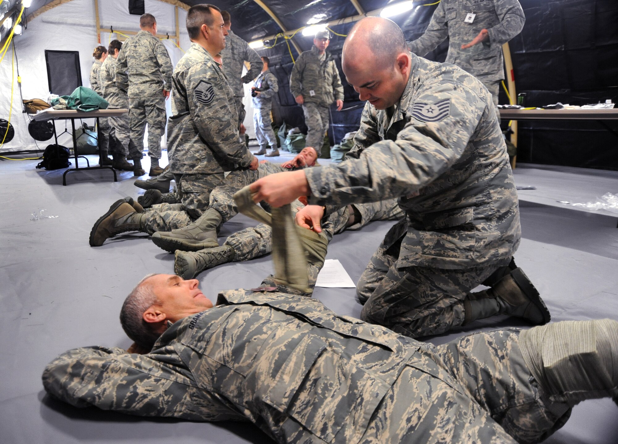 Oregon National Guard Tech. Sgt. George Sanders, right, applies a bandage to Maj. Paul Granada, left, during the AEF Skill Rodeo, April 12, 2015, Portland Air National Guard Base, Ore. Both Sanders and Granada are assigned to 142nd Fighter Wing Maintenance Group and are preparing for deployment with others members of the 142nd Fighter Wing. (U.S. Air National Guard photo by Tech. Sgt. John Hughel, 142nd Fighter Wing Public Affairs/Release)