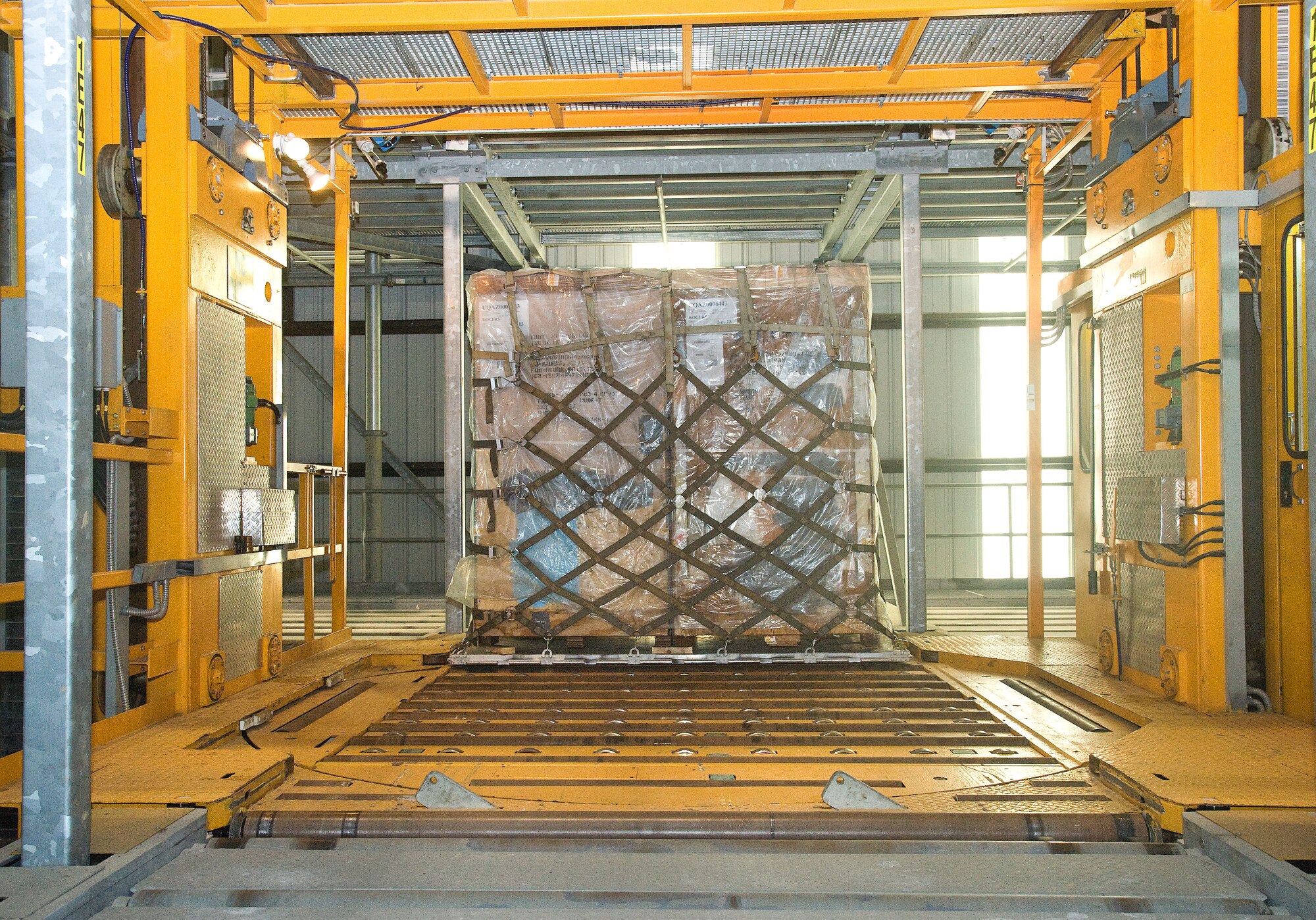 A pallet of cargo rolls onto a one of two elevating transfer vehicles May 4, 2015, at the 436th Aerial Port Squadron on Dover Air Force Base, Del. Pallets are temporarily housed in a multi-level pallet grid terminal where a computer system remembers exactly where the specific pallet is stored. When the pallet is ready to be loaded onto an aircraft, the ETV retrieves the pallet in the required order to be loaded onto a cargo loader, and then onto an aircraft. (U.S. Air Force photo/Roland Balik)