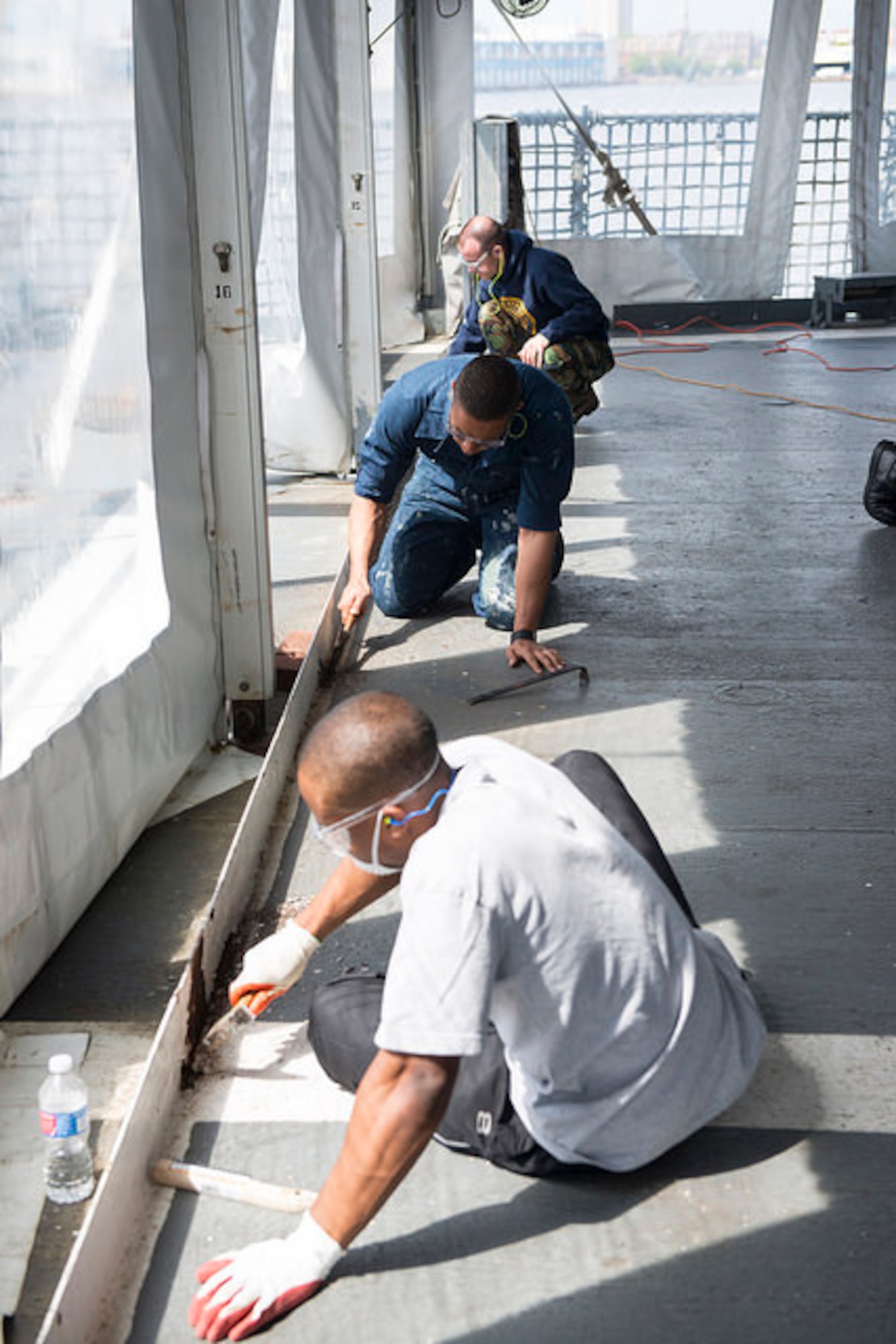 Sailors from Joint Base McGuire-Dix-Lakehurst remove paint and rust from the Battleship New Jersey, May 1, 2015. Service members volunteered to help restore the historic battleship, removing rust from the helicopter deck and hanging awnings throughout the ship. (U.S. Air Force photo by Airman 1st Class Joshua King)