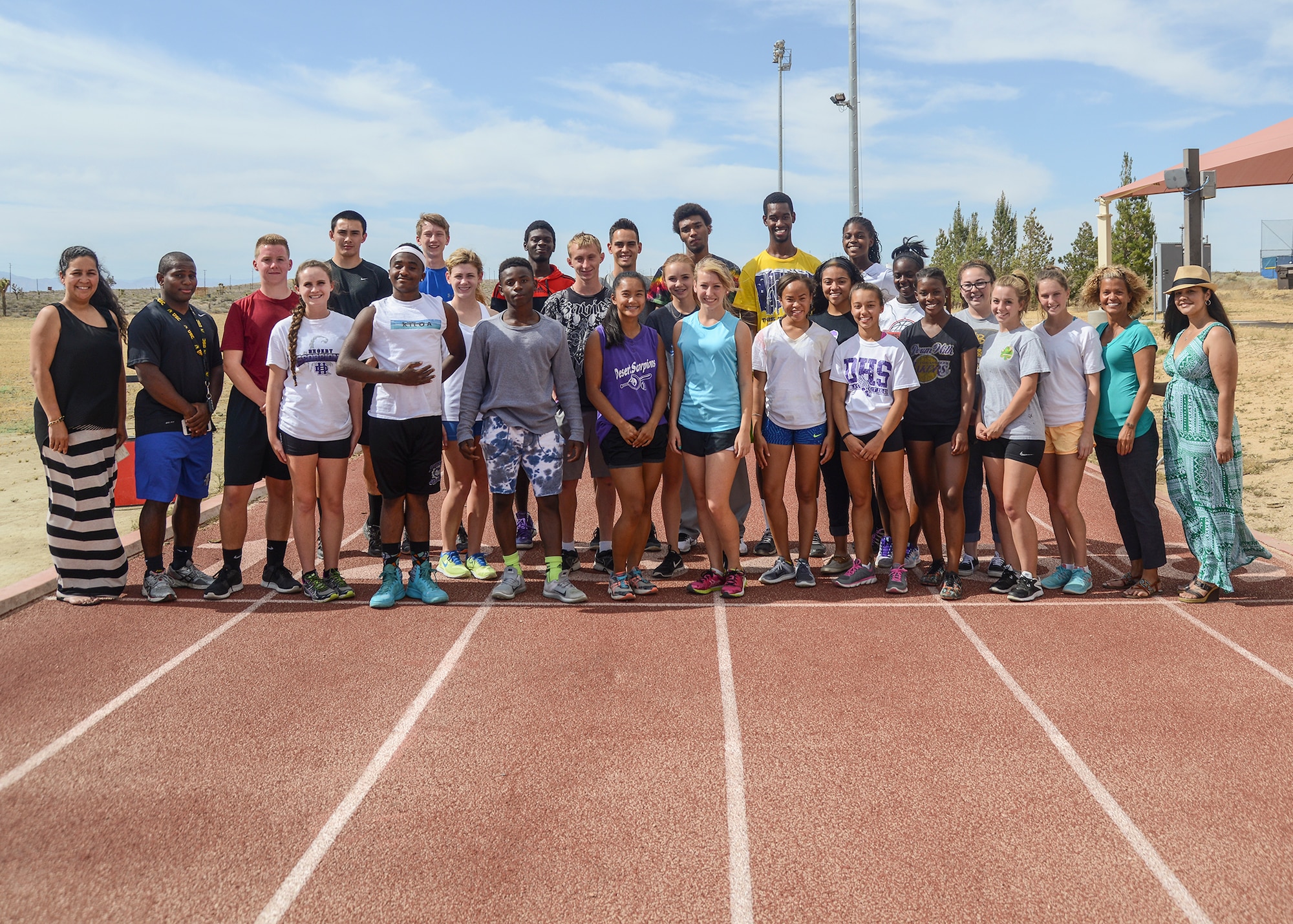 Edwards AFB's Enlisted Spouses Club treasurer, Andrea Guest (far right) and advisor Leslie Smith (far left) presented the Desert High School track team with $1,000 for safety equipment May 1. (U.S. Air Force photo by Rebecca Amber)