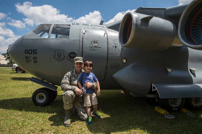 Staff Sgt. John Blankenship poses with his son in front of a replica C-17 Globemaster III during the annual base picnic May 1, 2015 at Joint Base Charleston, S.C. The two-day event included free food, live music, an inflatable obstacle course, a rock-climbing wall, a military working dog demo, prizes and demonstrations from local organizations. These organizations support service members throughout the year. Blankenship is a member of the 437th Aircraft Maintenance Squadron. (U.S. Air Force photo/Senior Airman Jared Trimarchi)