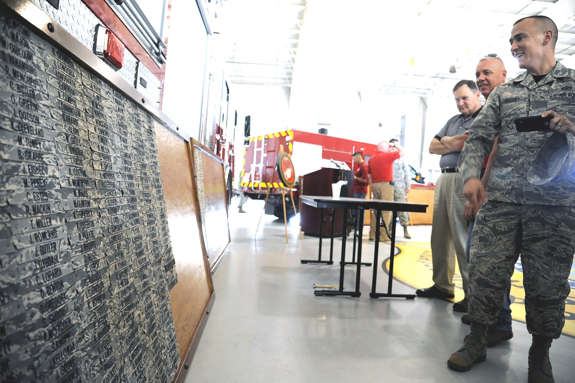 Attendees of the Louis F. Garland Department of Defense Fire Academy 20th anniversary ceremony admire the unveiled display board of past and present instructors at the academy high bay on Goodfellow Air Force Base, Texas, May 1, 2015. The objectives of the ceremony were to rededicate the opening of the academy on Goodfellow and celebrate the heritage of fire protection instructors. (U.S. Air Force photo by Tech. Sgt. Austin Knox/Released)