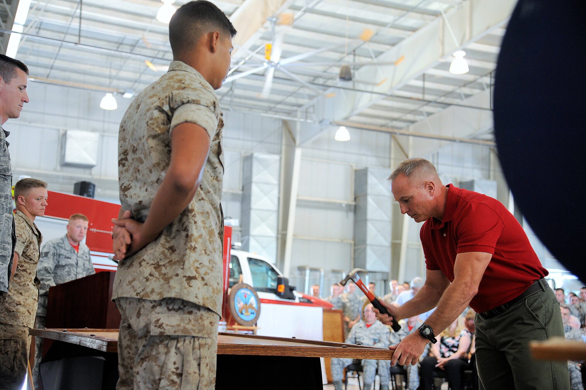 Bill Bockelman, 312th Training Squadron instructor, hammers his name tape onto a display board at the Louis F. Garland Department of Defense Fire Academy high bay on Goodfellow Air Force Base, Texas, May 1, 2015. The display honors the 20-year heritage of the fire academy with the names of past and present instructors. (U.S. Air Force photo by Tech. Sgt. Austin Knox/Released)