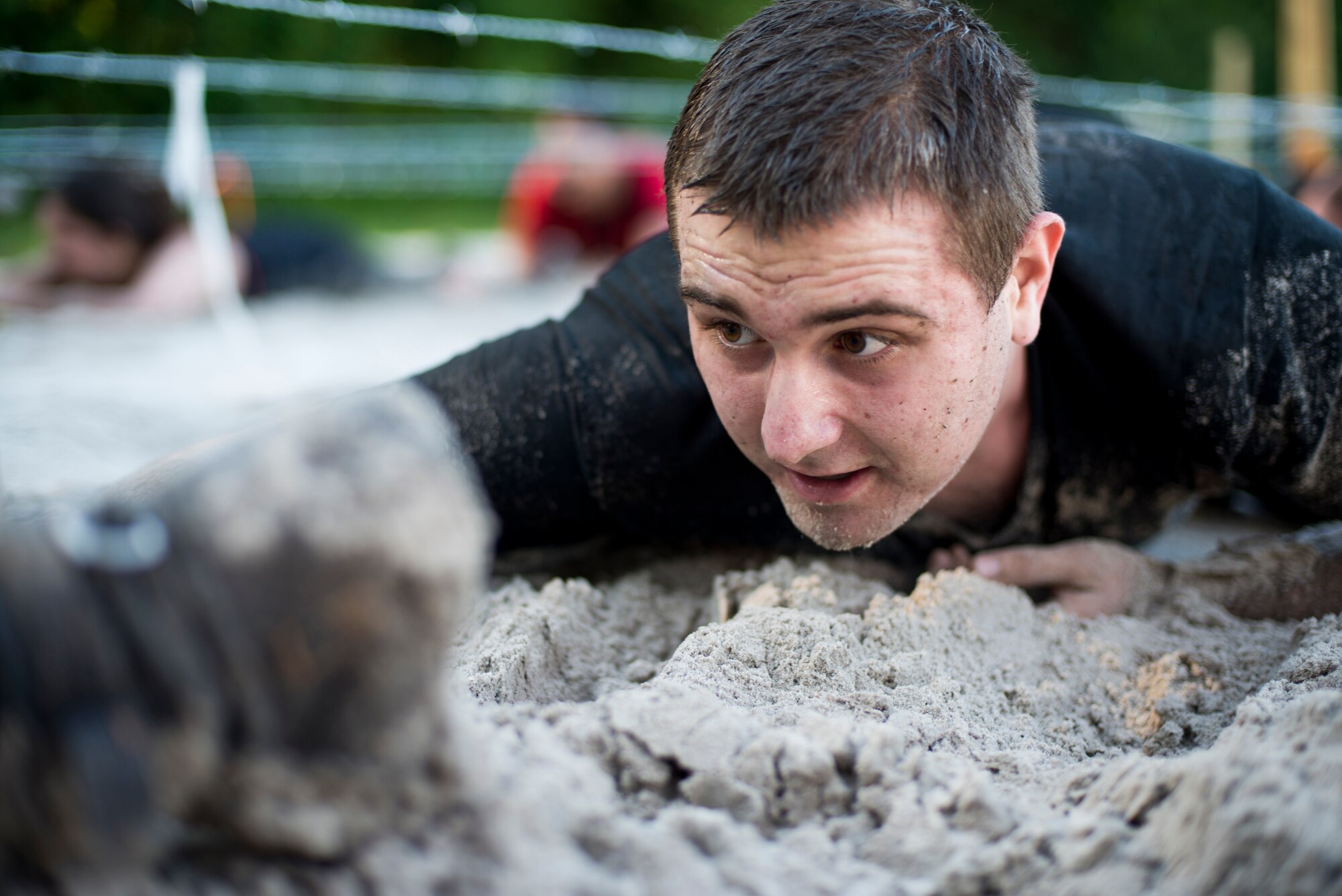 U.S. Air Force Airman 1st Class Ryan Clark, 23d Communications Squadron, crawls through a barbed wire sand pit during the 2015 Moody Mudder May 2, 2015, in Ray City, Ga. Following the barbed wire low crawl, Clark’s next challenge was to leap over a large fire pit. (U.S. Air Force photo by Airman 1st Class Dillian Bamman/Released)