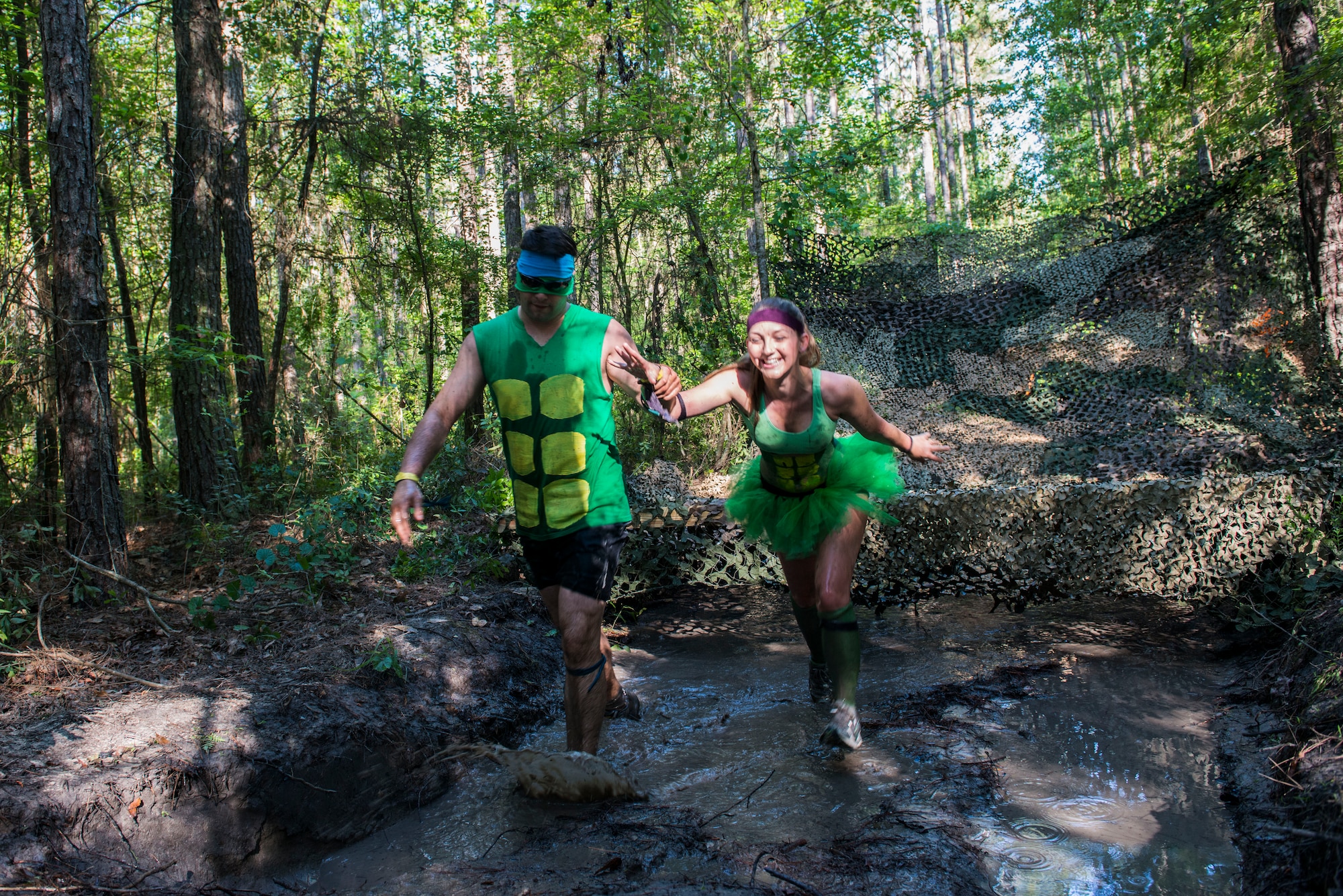 Two Moody Mudder participants recover after crawling through a mud pit during the 2015 Moody Mudder May 2, 2015, in Ray City, Ga. Runners participated in many obstacles throughout the run such as a climbing wall, fire pit, low crawls, monkey bars and rock hills. (U.S. Air Force photo by Airman 1st Class Dillian Bamman/Released)