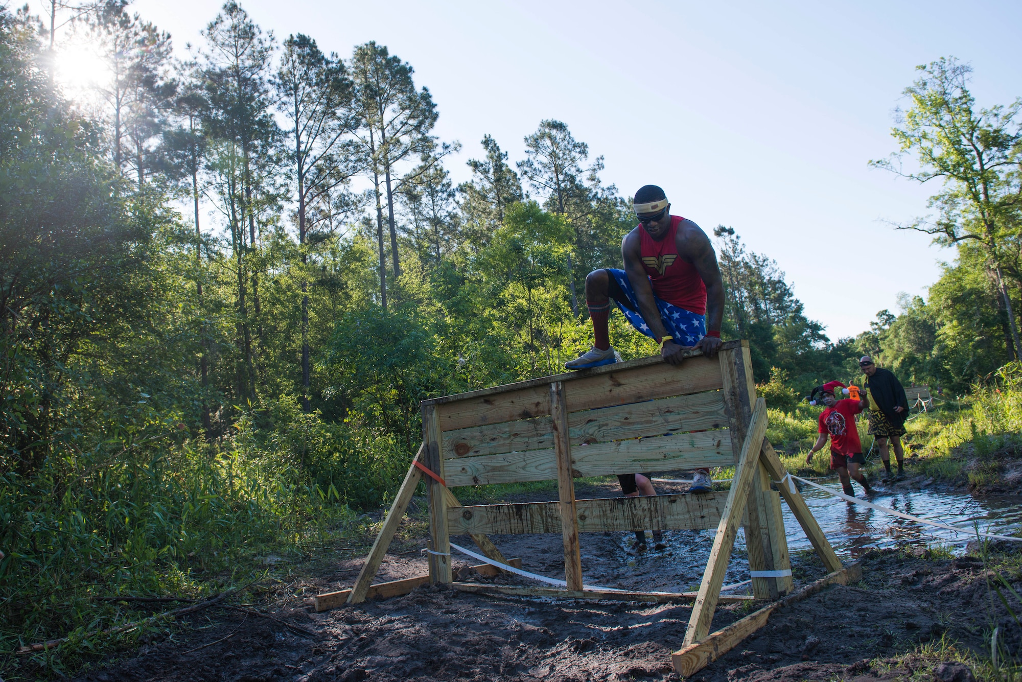 A runner climbs over a lateral obstacle during the 2015 Moody Mudder May 2, 2015, in Ray City, Ga.  Runners dressed up in costumes for this year’s theme of superheroes. (U.S. Air Force photo by Airman 1st Class Dillian Bamman/Released)
