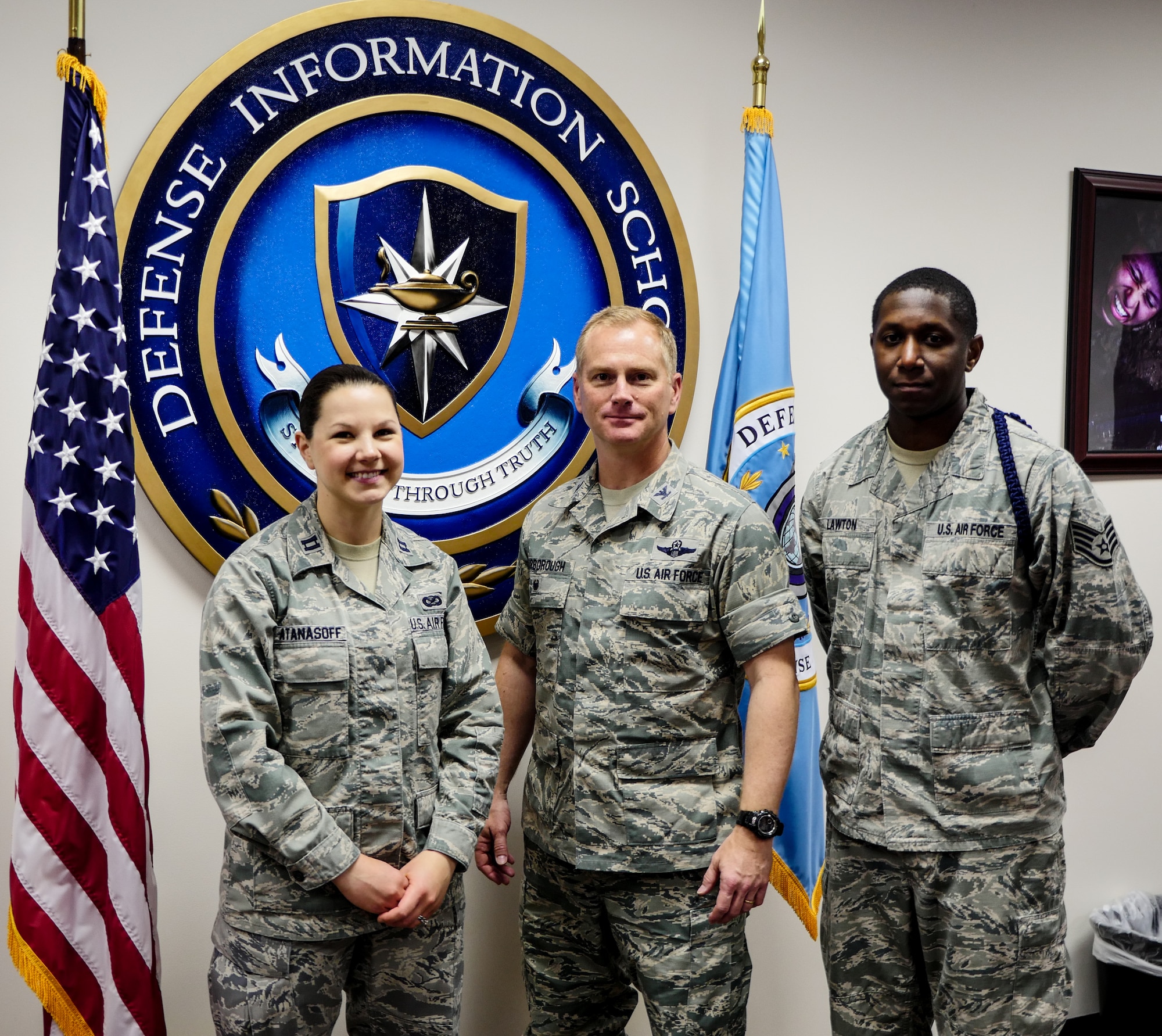 Capt. Kathleen Atanasoff, Detachment 2, 336th Training Squadron commander, Col. Dennis Scarborough, 81st Training Wing vice commander, and Staff Sgt. Cedric Lawton, Det. 2, 336th TRS military training leader, pose for picture in front of the Defense Information School emblem, May 1, 2015, Fort Meade, Md. Scarborough visited DINFOS to learn about the different classes offered to Air Force students, interact with Det. 2 members and DINFOS students. (DoD photo by Joseph Coslett)