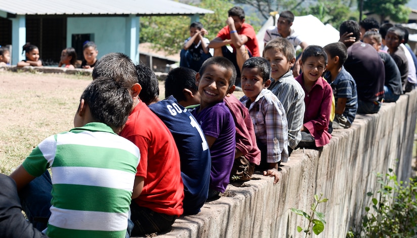 SOTO CANO AIR BASE, Honduras – Children sit atop a wall waiting for hikers from Joint Task Force-Bravo and the Honduran Air Force Academy to complete the 3.2-mile ascent to the village of El Misterio, Honduras April 18, 2015. Upon arrival, the hikers gave 3,000 pounds of rice and other goods to the villagers there, to show good will and build trust in Honduras. (U.S. Air Force photo by Staff Sgt. Jessica Condit)