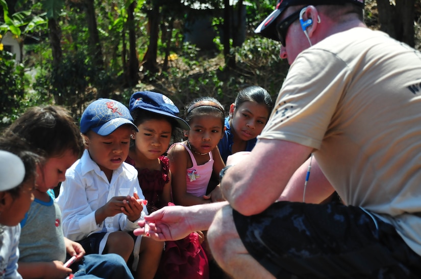 SOTO CANO AIR BASE, Honduras – U.S. Army Col. Kirk Dorr, Joint Task Force-Bravo commander, gives candy to a group of children from the mountain village of El Misterio, Honduras, April 18, 2015, as part of a 6.4-mile round trip chapel hike. Members of Joint Task Force-Bravo and the Honduran Air Force Academy carried 3,000 pounds of rice and other goods to El Misterio’s villagers, to show goodwill and build trust in Honduras. (U.S. Air Force photo by Capt. Christopher Love)