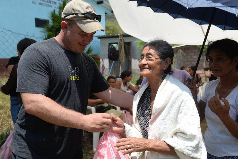 SOTO CANO AIR BASE, Honduras – Sgt. Maj. Jamie Wells, Joint Task Force-Bravo operations sergeant major, presents a bag of rice and other items to an elderly villager from El Misterio, Honduras, during a JTF-B chapel hike April 18, 2015. This was the 60th iteration of the Joint Task Force-Bravo chapel hike program, which has delivered more than 217,000 pounds of donated goods to people in need in remote areas, to show good will and build trust in Honduras.  (U.S. Air Force photo by Staff Sgt. Jessica Condit)