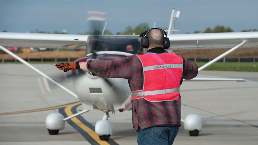 Mark Tetreault, 436th Aircraft Maintenance Squadron transit alert, marshals a privately owned aircraft during the 2015 Dover Air Force Base Mid-Air Collision Avoidance Fly-in May 2, 2015, at Dover AFB, Del. Twenty-nine aircraft and 68 pilots participated in the fly-in. (U.S. Air Force photo/Airman 1st Class Zachary Cacicia)