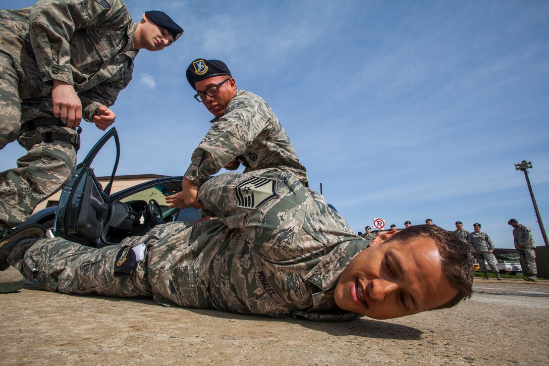 Airman 1st Class Justin Rodriguez, center, and Senior Airman Jamie Rivera, left, restrain role player Master Sgt. Rafael Morales Jr., all with the 108th Security Forces Squadron, 108th Wing, New Jersey Air National Guard, during high risk traffic stop scenario training at Joint Base McGuire-Dix-Lakehurst, N.J., April 19, 2015. The required annual training, which emphasized how to deal with a variety of traffic stops ranging from routine to high risk, is comprised of one day of classroom training and one day of practical hands-on training using vehicles and role players. Through the preparation, the Airmen are better able to handle whatever scenario they encounter in real life. (U.S. Air National Guard photo by Master Sgt. Mark C. Olsen/Released)