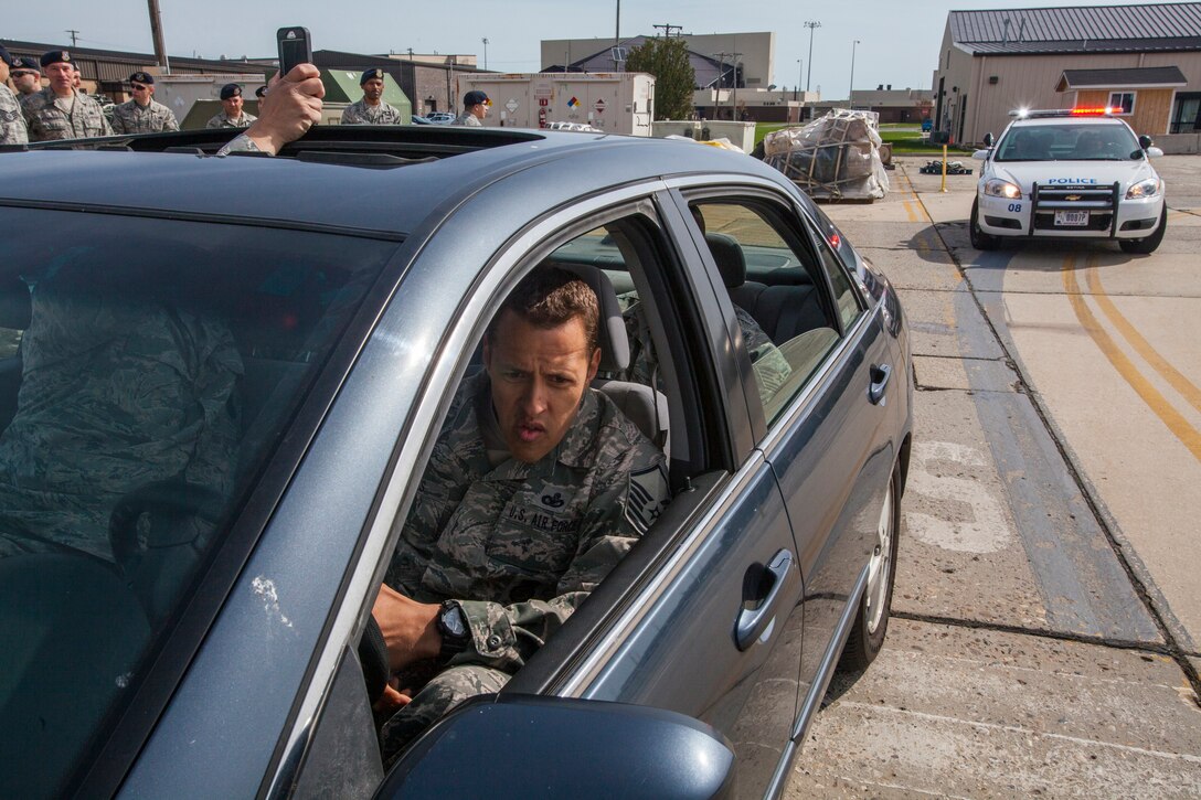 Master Sgt. Rafael Morales Jr., 108th  Security Forces Squadron, 108th Wing, New Jersey Air National Guard, serves as a role player, while another role player pretends to record the event, in a high risk traffic stop training scenario at Joint Base McGuire-Dix-Lakehurst, N.J., April 19, 2015. The required annual training, which emphasized how to deal with a variety of traffic stops ranging from routine to high risk, is comprised of one day of classroom training and one day of practical hands-on training using vehicles and role players. Through the preparation, the Airmen are better able to handle whatever scenario they encounter in real life. (U.S. Air National Guard photo by Master Sgt. Mark C. Olsen/Released)