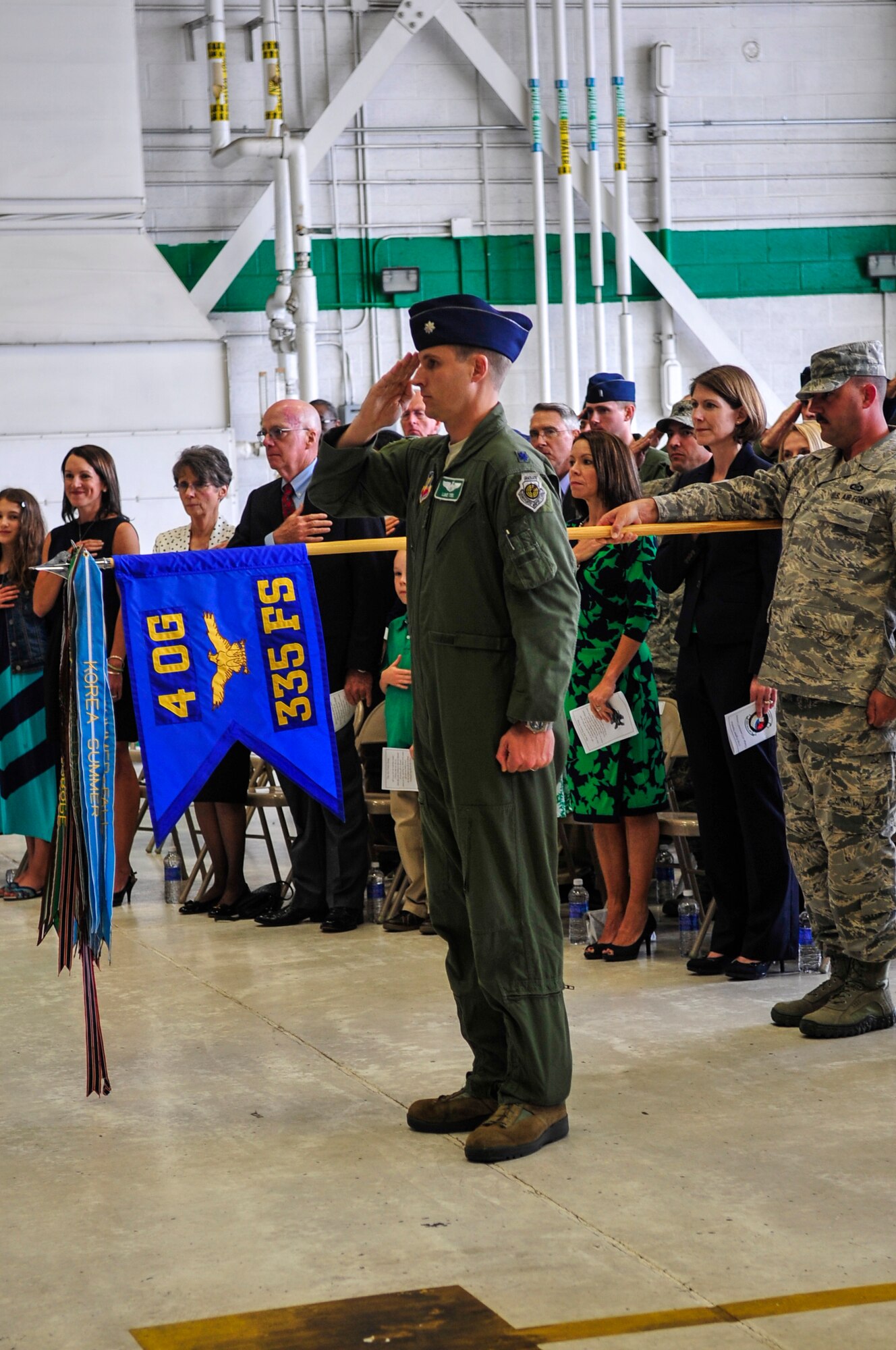 Lt. Col. Lucas Teel, 335th Fighter Squadron director of operations, along with family, friends and Airmen from the 335th FS render courtesies to the American flag during a change of command ceremony, May 1, 2015, at Seymour Johnson Air Force Base, North Carolina. Base and community leadership, along with Airmen from the 335th FS gathered to witness the traditional passing of the guidon. (U.S. Air Force photo/Airman Shawna L. Keyes)
