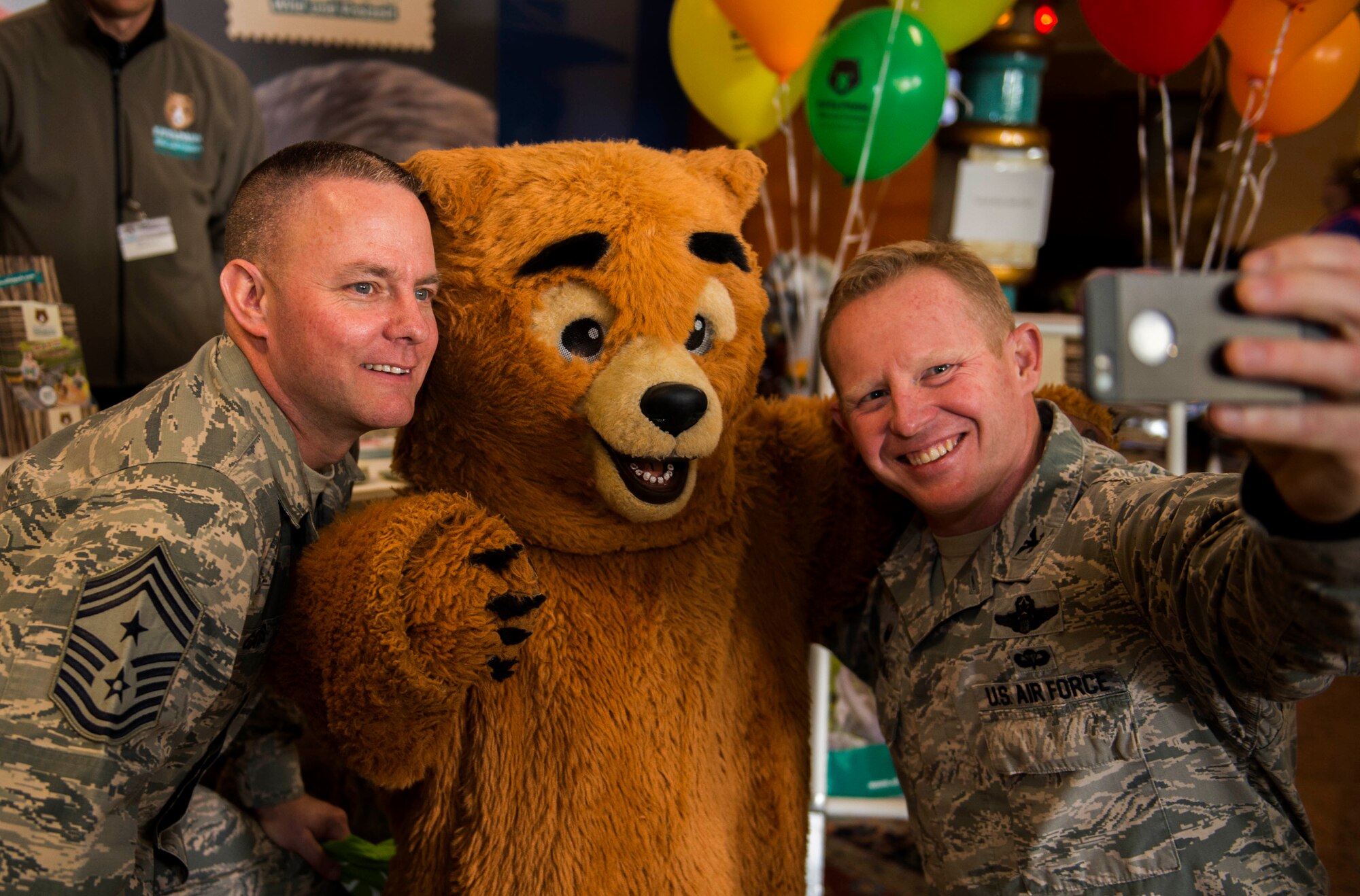 U.S. Air Force Col. Joe McFall, 52nd Fighter Wing commander, right, and U.S. Air Force Chief Master Sgt. Brian Gates, 52nd Fighter Wing command chief, left, take a photo with an exhibitor in a bear costume during the 11th annual Explore the Eifel information and adventure fair at Club Eifel on Spangdahlem Air Base, Germany, April 26, 2015. Exhibitors, local community leaders, area officials, Bitburg County representatives, Host Nation Council representatives, honorary commanders, community volunteers, travel and tourist office agents and private establishments attended the event. (U.S. Air Force photo by Airman 1st Class Timothy Kim/Released)