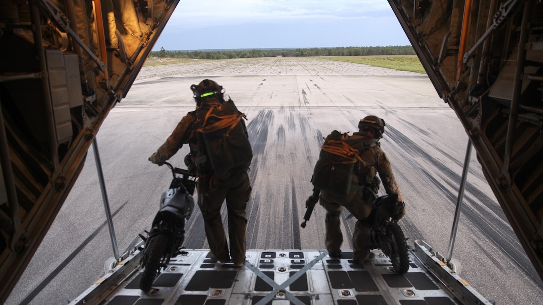 Two 123rd STS personnel off load 50 cc mini bikes to stage on a runway at an Eglin Air Force Base drop zone, prior to a static line jump and jump clearing team mission from a KC-130J Super Hercules belonging to Marine Aerial Refueler Transport Squadron 252, during Emerald Warrior 2015, April 28, 2015.  The mini bikes are used to patrol down the air strip before the plane lands to ensure there is no debris or hostile forces near the landing zone. Emerald Warrior is a joint exercise led by Air Force Special Operations Command that provides pre-deployment training for U.S. and partner nation special operations forces and interagency elements.  (U.S. Marine Corps photo by Cpl. Alexander Mitchell/released)