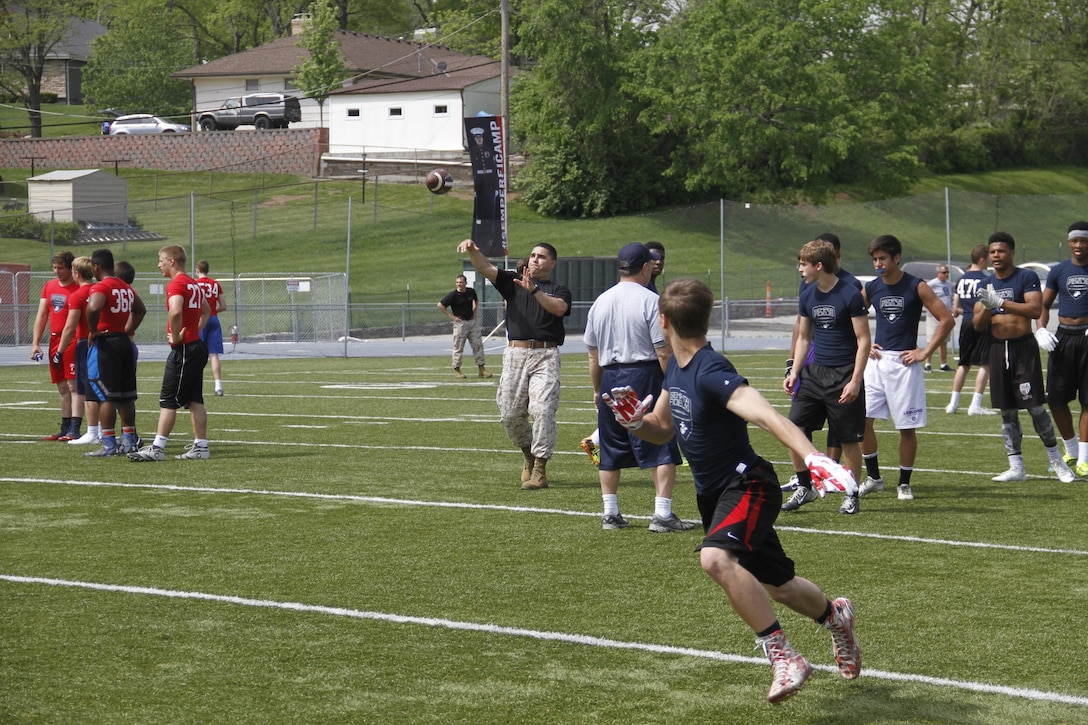 Sergeant Matthew Garcia, a Marine Corps Recruiting Station Kansas City recruiter, throws a football downfield to receivers as part of a route-running drill during the Semper Fidelis All-American Football Camp at Rockhurst High School's Vincent P. Dasta Memorial Stadium May 3, 2015.  