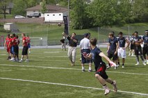Sergeant Matthew Garcia, a Marine Corps Recruiting Station Kansas City recruiter, throws a football downfield to receivers as part of a route-running drill during the Semper Fidelis All-American Football Camp at Rockhurst High School's Vincent P. Dasta Memorial Stadium May 3, 2015.  