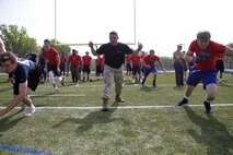 Sergeant Jose Marrufo, a Marine Corps Recruiting Station Kansas City recruiter, motivates football players to push through a sprint drill during the Semper Fidelis All-American Football Camp at Rockhurst High School's Vincent P. Dasta Memorial Stadium May 3, 2015. Approximately 195 players from across Missouri, Kansas, Arkansas, Nebraska, Illinois and Missippi took part in the all-day camp. NFL coaches were on hand to provide critical football skills and guidance to the camp attendees. 