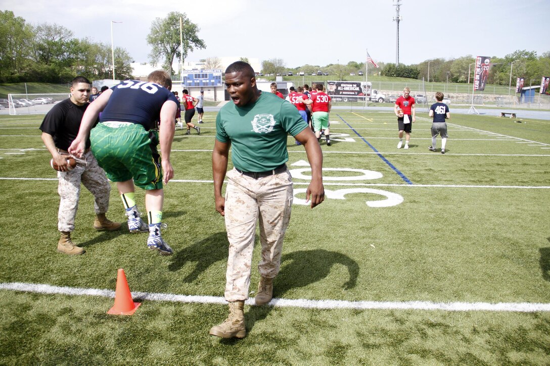 Sergeant Anthony L. Williams, a Receiving Company, Recruiting Training Regiment, Marine Corps Recruit Depot San Diego drill instructor, instructs football players through a drill during the Semper Fidelis All-American Football Camp at Rockhurst High School's Vincent P. Dasta Memorial Stadium May 3, 2015. Ninth, 10th, and 11th grade players participated in the camp, which covered skill drills and sets concerning both offense and defense. 