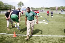 Sergeant Anthony L. Williams, a Receiving Company, Recruiting Training Regiment, Marine Corps Recruit Depot San Diego drill instructor, instructs football players through a drill during the Semper Fidelis All-American Football Camp at Rockhurst High School's Vincent P. Dasta Memorial Stadium May 3, 2015. Ninth, 10th, and 11th grade players participated in the camp, which covered skill drills and sets concerning both offense and defense. 
