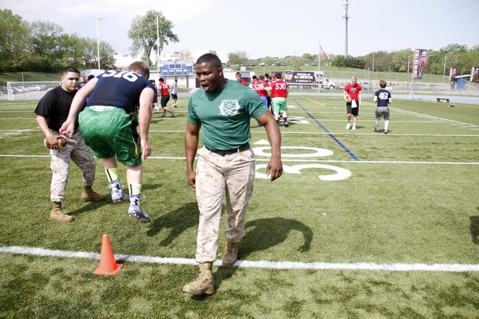 Sergeant Anthony L. Williams, a Receiving Company, Recruiting Training Regiment, Marine Corps Recruit Depot San Diego drill instructor, instructs football players through a drill during the Semper Fidelis All-American Football Camp at Rockhurst High School's Vincent P. Dasta Memorial Stadium May 3, 2015. Ninth, 10th, and 11th grade players participated in the camp, which covered skill drills and sets concerning both offense and defense. 