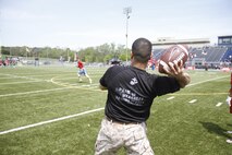Sergeant Matthew Garcia, a Marine Corps Recruiting Station Kansas City recruiter, throws a football downfield to receivers as part of a route-running drill during the Semper Fidelis All-American Football Camp at Rockhurst High School's Vincent P. Dasta Memorial Stadium May 3, 2015.  