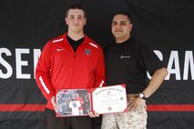 Sergeant Matthew Garcia, a Marine Corps Recruiting Station Kansas City recruiter, poses with Jaycee Pummill, the former long snapper for the 2014 Blue Springs High School Wildcats football team and a 2015 Semper Fidelis All-American Bowl participant, at the end of the Semper Fidelis All-American Camp at Rockhurst High School's Vincent P. Dasta Memorial Football Stadium May 3, 2015. Pummill received a certificate for participating in the bowl earlier this year. Pummill will continue his football career at Virginia Union University. 