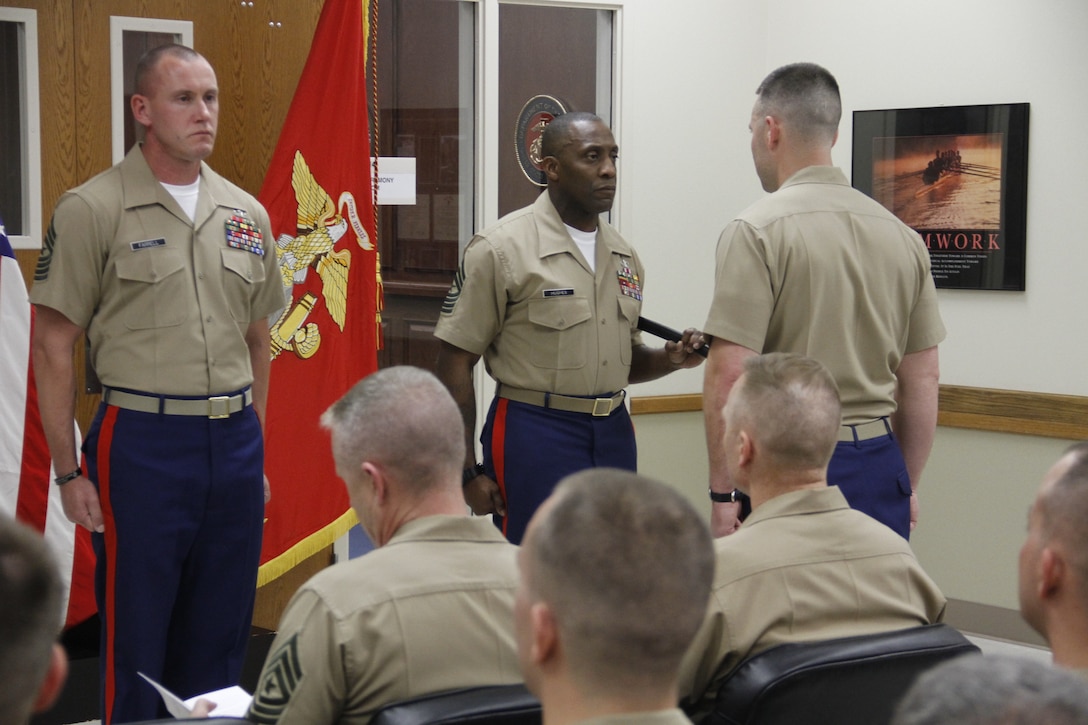 Sergeant Major Johnnie Hughes, outgoing Marine Corps Recruiting Station Kansas City sergeant major, prepares to relinquish the sword of office to Maj. Alfred L. Butler IV, RS Kansas City commanding officer, who will then pass the sword to Sgt. Maj. Christopher A. Farrell, oncoming RS Kansas City sergeant major during RS Kansas City's sergeant major relief and appointment at the Kansas City Military Entrance Processing Station April 17, 2015. 