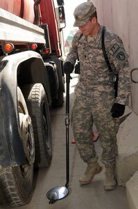 Spc. Adam Hatch of the Maine Army National Guard's 1136th Transportation Company checks the underside of a truck for bombs, drugs or any other harmful substance that might cause a threat to Camp Eggers in Kabul, Afghanistan, Oct. 7, 2010. Hatch, a mobile vehicle and cargo inspection system operator, and other members of the 1136th provide force protection for Camp Eggers and New Kabul Compound to ensure the safety of the personnel who live and work at these camps.