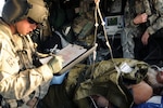 Sgt. 1st Class David Jacob, senior flight medic for the Louisiana National Guard writes information about a patient that is being transported an Afghan Army soldier. The soldiers of F Company fly into hostile fire areas to pick up and transport patients to safety, and are able to perform many different procedures while in the air.